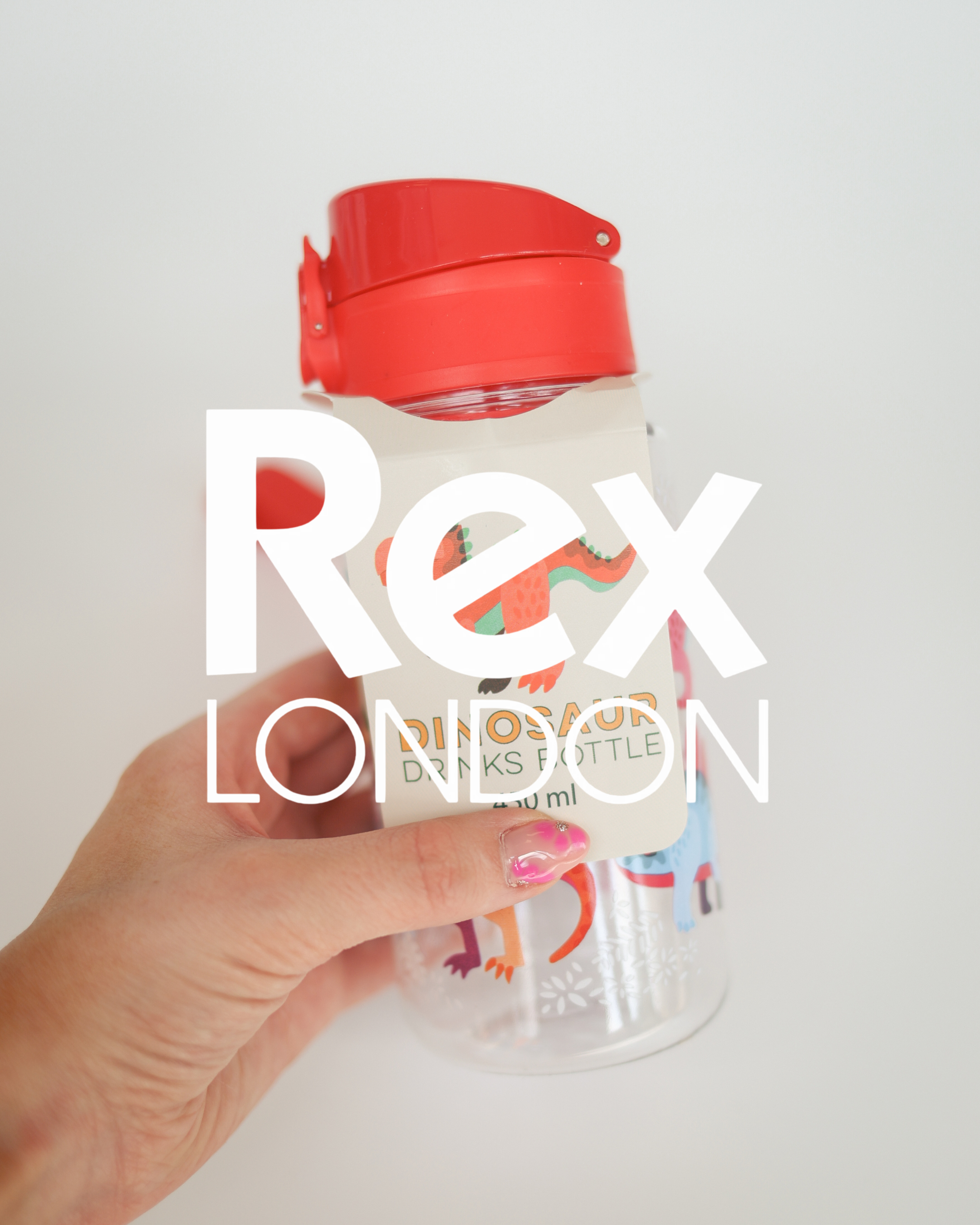 Rex London Dinosaur kids drinks bottle with red flip-top lid, 450ml, held in hand showing colourful dinosaur design