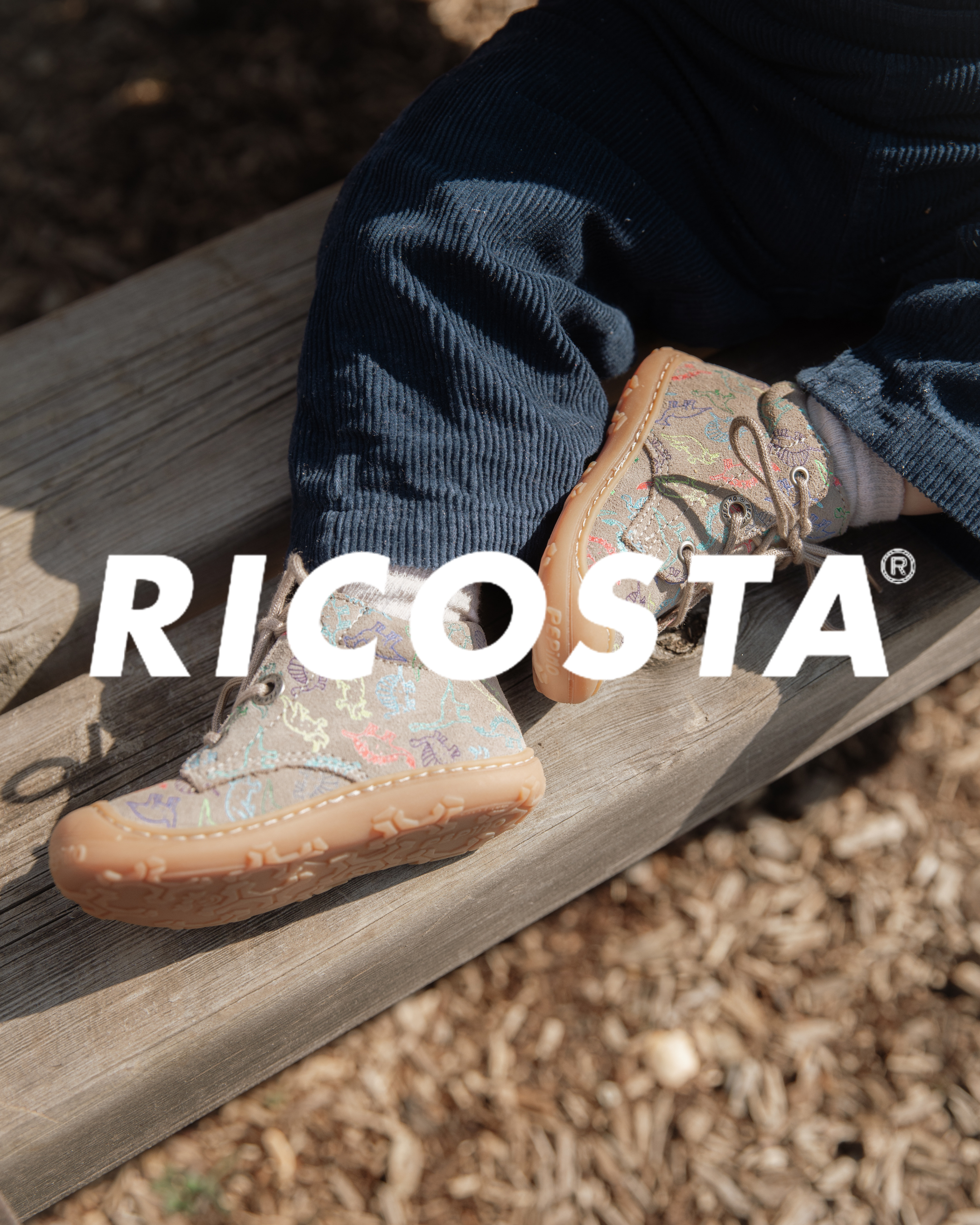 Ricosta children's patterned lace-up ankle boots with colourful embroidery, worn with navy corduroy trousers on wooden steps.