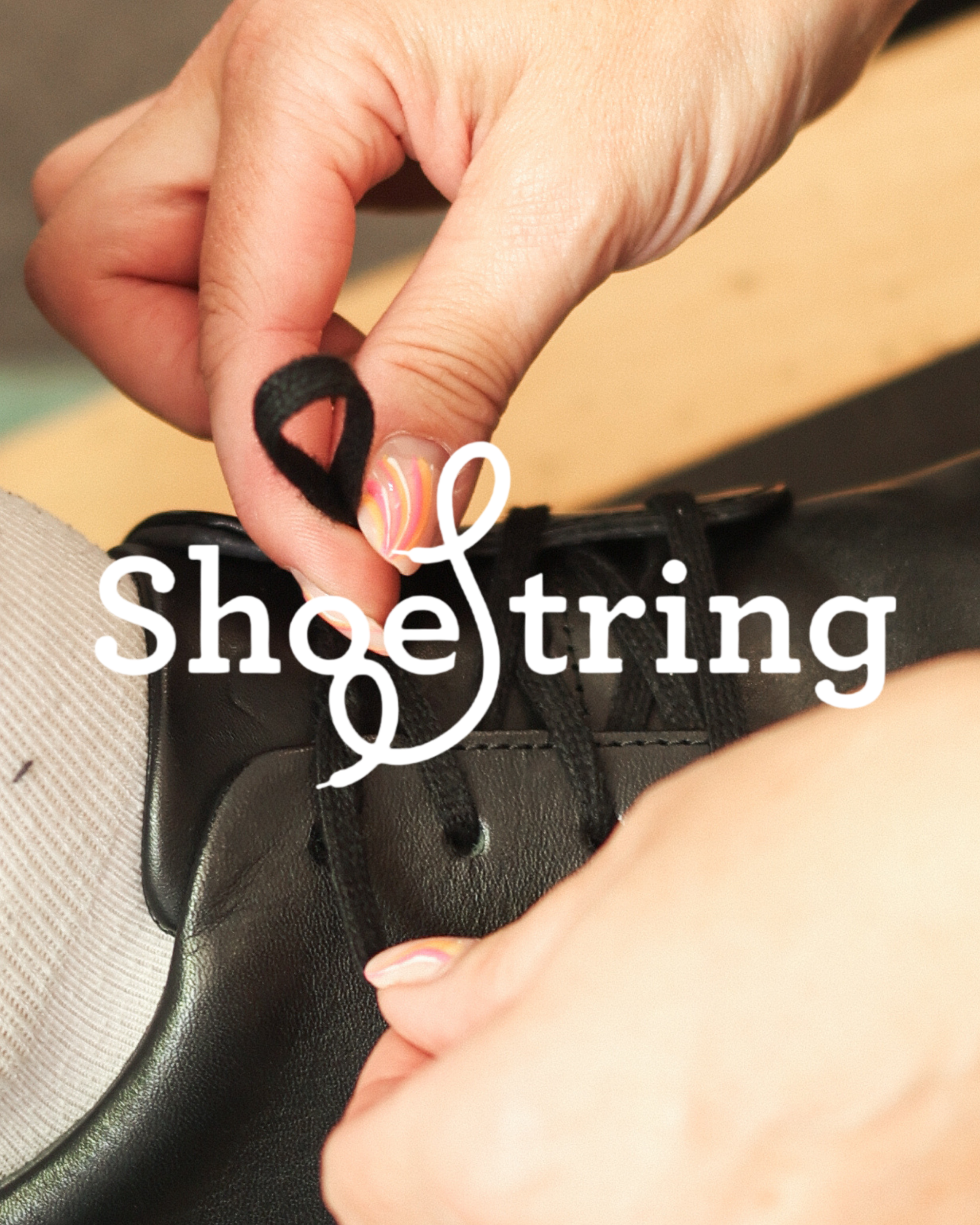 Hands tying black laces on a black leather shoe, with the Shoestring brand logo overlaid in white text.