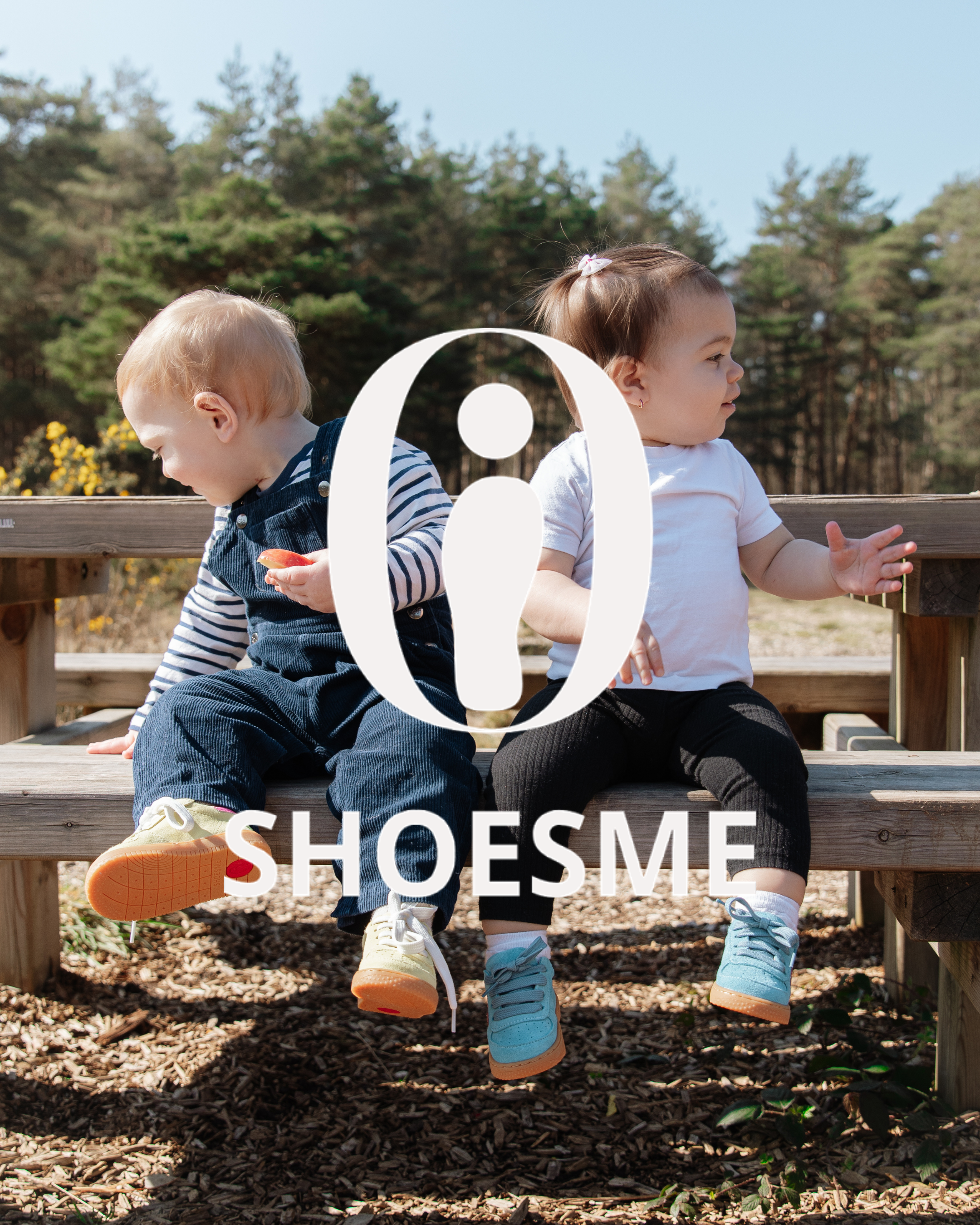 Two toddlers sitting on a wooden bench outdoors wearing Shoesme sneakers in cream and blue colourways.